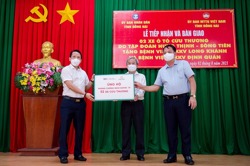 Đại diện Tập đoàn Hưng Thịnh trao bảng tượng trưng 2 xe cứu thương cho ông Võ Tấn Đức - Phó Chủ tịch UBND tỉnh Đồng Nai (bên phải) và ông Cao Văn Quang - Chủ tịch MTTQ Việt Nam tỉnh Đồng Nai (ở giữa) nhằm hỗ trợ công tác phòng, chống dịch 